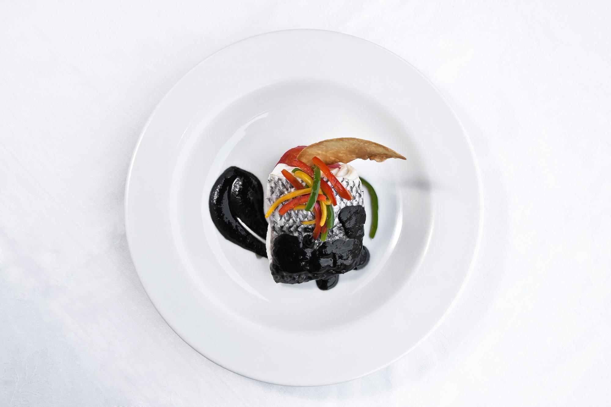 Chef plating a luxurious dish on dark surface